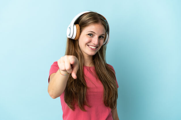 女人年轻的白人妇女在蓝色背景下听音乐休闲成人声音