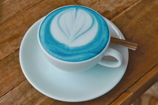 牛奶特写蓝色拿铁艺术木桌上茶碟浓缩咖啡桌子