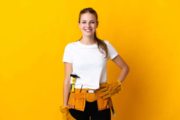 骄傲被隔离在黄色背景上的年轻电工女人笑了工具年轻木匠