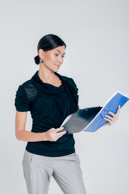 员工一个有魅力的女商人的肖像 拿着一个文件夹 里面有灰色背景的文件文件夹自信黑发