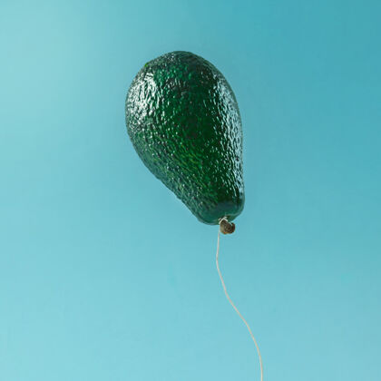 空气蓝色表面上的鳄梨果实做成的气球抽象新鲜庆祝