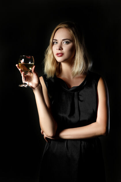 礼服美丽的金发女人 一杯黑底白葡萄酒感性年轻庆典