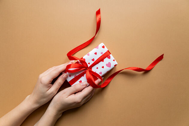 礼品包装女性手持礼品盒包装盒的俯视图 背景是平放的装饰浪漫包装