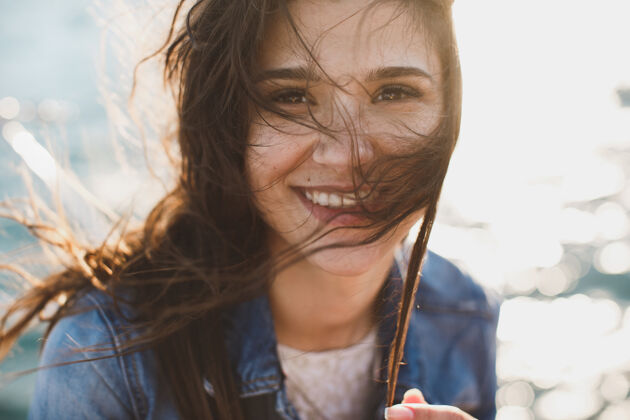 微笑美丽的年轻女子站在海边 背靠着碧蓝的大海 头发在微风中飘扬生活方式欢呼模型