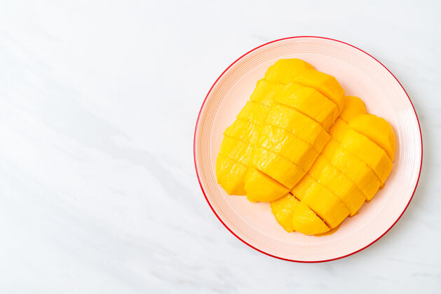 热带新鲜的金色芒果片放在盘子里黄色多汁美食