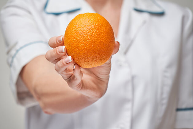 健康饮食营养师医生健康的生活方式理念-持有新鲜的有机橙子水果保持饮食制服