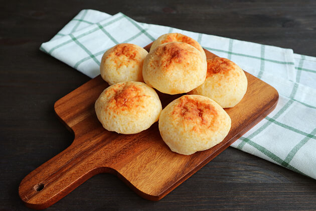 新鲜自制paodequeijo或巴西奶酪面包放在木制的面包板上很多堆面包