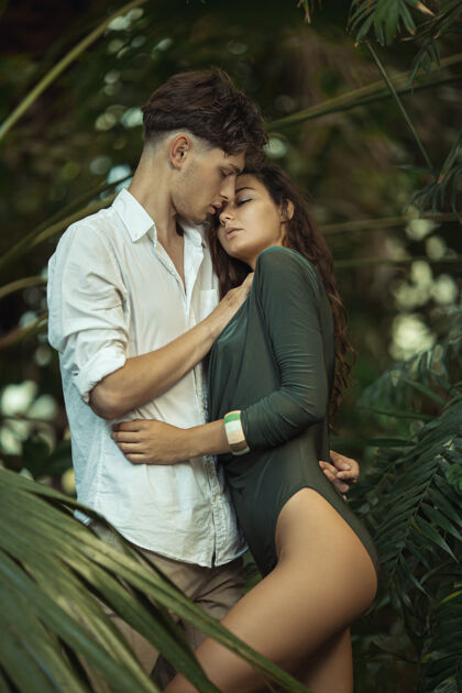 年轻一对浪漫的情侣在热带丛林中的异国植物中棕榈花园一起