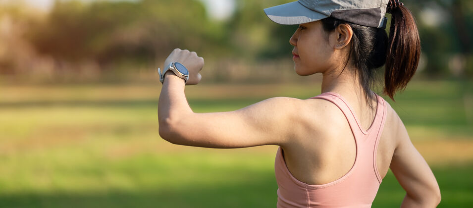 慢跑年轻成年女性在公园户外跑步时在sportsmartwatch上检查时间和有氧心率 跑步女性在公园慢跑晨练 科技 生活方式和锻炼健康女性私人教练