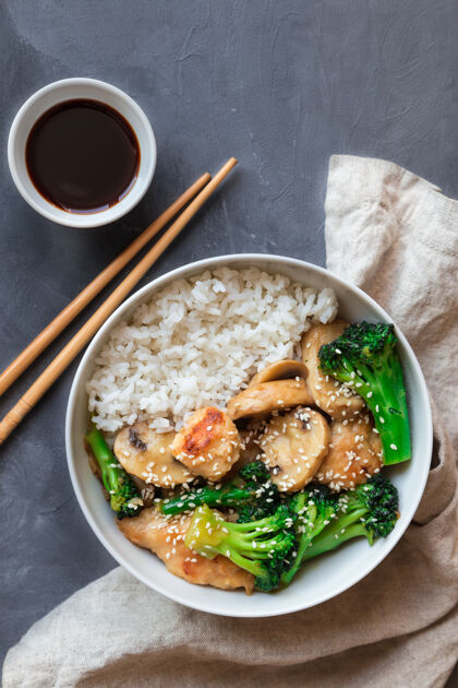 蔬菜烧鸡肉 花椰菜和蘑菇在灰色水泥上用白米在碗里炒米饭营养餐巾纸