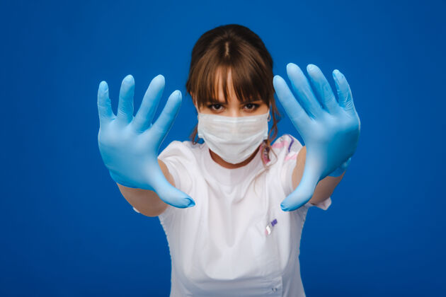 橡胶一个女医生戴着医学面具站在那里 被隔离在蓝色的背景上医疗保健治疗成人