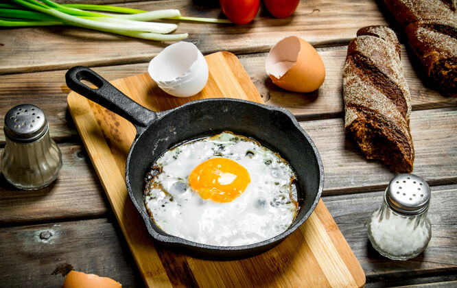 美食在平底锅里煎鸡蛋 配上面包 西红柿和葱蛋黄蛋白质油
