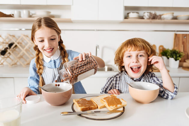 厨房巧克力燃油正极可爱可爱的兄弟姐妹们在上学前有丰富的营养早餐 包括花生酱三明治和谷类食品围裙早餐孩子