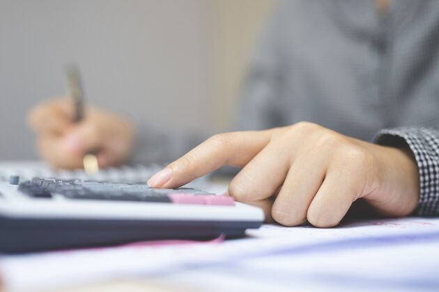 数字女商人或会计手持铅笔在办公室办公计算财务数据报告 会计凭证和笔记本电脑 商业概念特写热桌面工作区