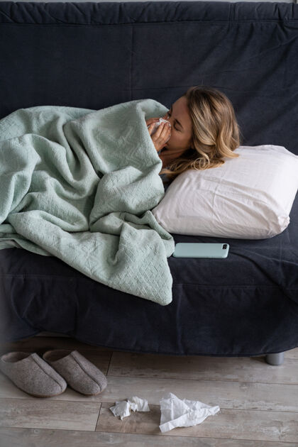 沙发生病的妇女在家躺在床上患有过敏 流感症状 发烧 打喷嚏在纸纸巾流感纸巾女人