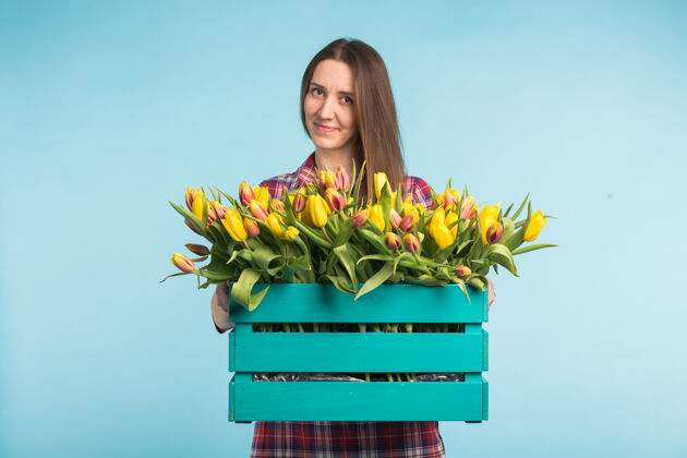 束快乐的高加索年轻女子拿着蓝色表面郁金香的盒子花店花惊喜