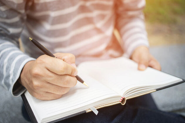 日记一位年轻女子坐在大理石上椅子使用在公园里用笔把讲稿笔记本写进书里公共.top查看信息女性户外