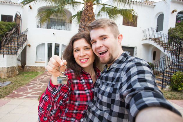 拥抱物业 房地产和租金概念-快乐有趣的年轻夫妇展示他们的新房子的钥匙房产房子钥匙
