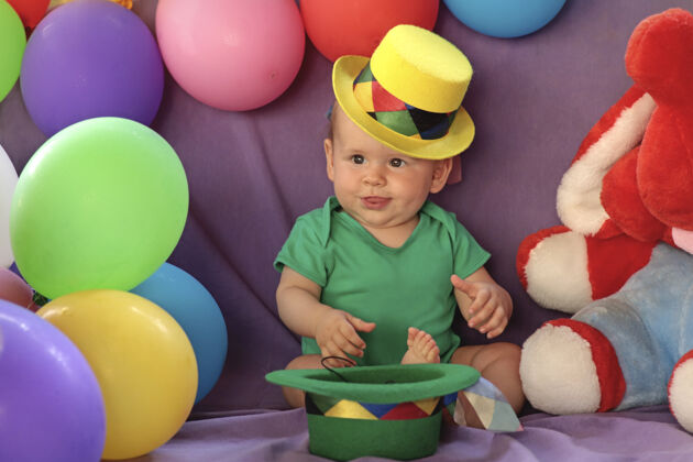气球一个小孩坐在一个有趣的节日气氛与气球和黄色帽子男孩玩具坐着
