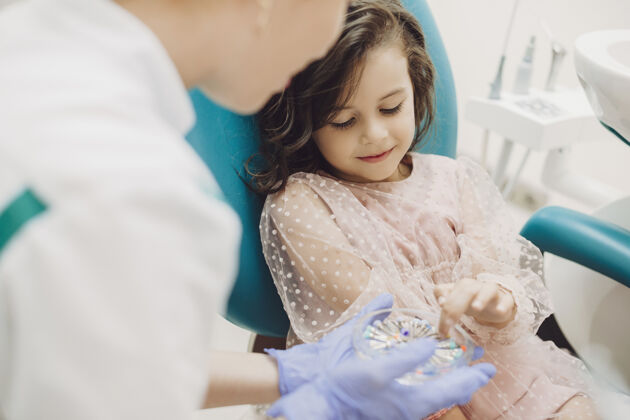 椅子一个可爱的小女孩用手指展示了儿科口腔医生应该做什么工作女人女孩牙医