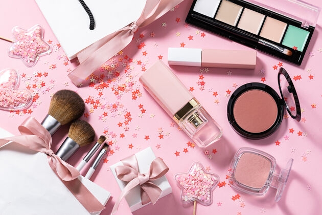 产品各种装饰性化妆品 香水 化妆刷和礼品盒和粉红色粉彩桌上闪亮的装饰品调色板专业阴影