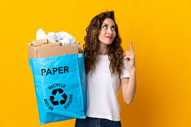 想法年轻女子拿着一个装满废纸的回收袋 把回收隔离在黄色的指尖上 真是个好主意保护指向循环