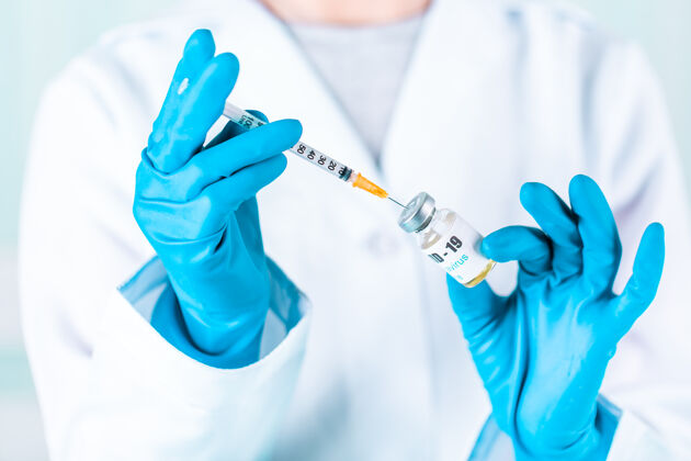 药物女医生或护士穿着制服 戴着手套 戴着口罩 在实验室里拿着带有冠状病毒疫苗标签的药瓶疫苗瓶疾病治疗药品
