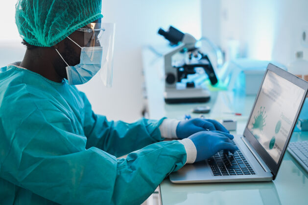 非裔美国人非洲男医生在实验室医院里用笔记本电脑工作-注意右手微生物学实验室预防