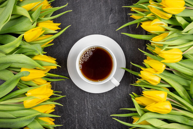 春天春天的公寓里铺着黄色的郁金香 白色的杯子里放着红茶 放在深色的水泥石头上植物学花浪漫