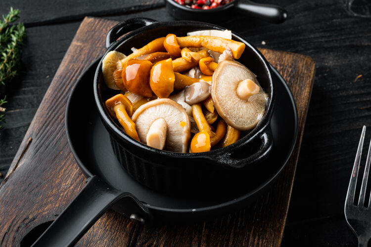 油发酵食品：蘑菇保鲜套 黑木桌背景铁锅牛肝菌健康