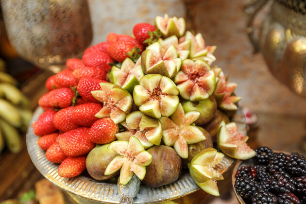 饮食草莓和蜂蜜无花果在一个古老的铜美食糖果比喻地切水果特写细节无花果