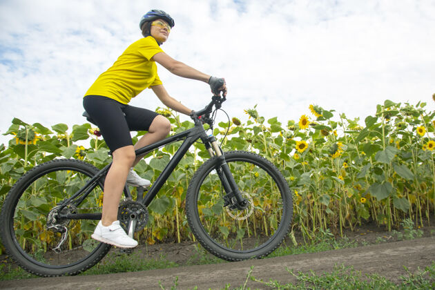 自行车手骑自行车的美女骑着向日葵在草地上自行车健活方式和运动休闲和爱好自然骑行自行车