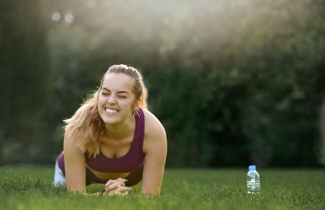 女人年轻的健身妇女在日落时在绿草上做木板夏天健活方式.微笑.美国!女人 绿色 自然 女孩 健身 草地 微笑 运动 人 瓶子 公园 健康 运动 训练 户外 年轻 脚 运动员 阳光 木板 活跃 长发 金发 户外 慢跑 白种人 复制空间