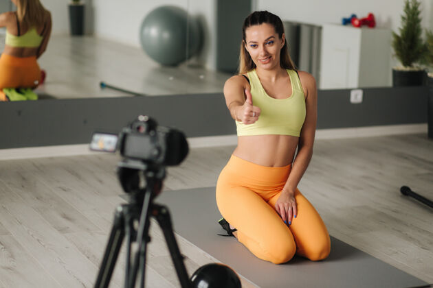 姿势女健身教练在健身房训练时用摄像机录视频室内概念生活方式影响运动和娱乐地板成人健康