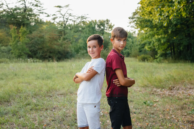 友谊两个快乐的小男孩站在公园里微笑着户外林间空地行动