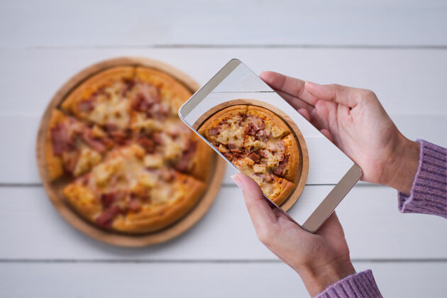 食物手拿毛衣的女人摄影披萨智能手机快食品和科技概念小吃移动午餐