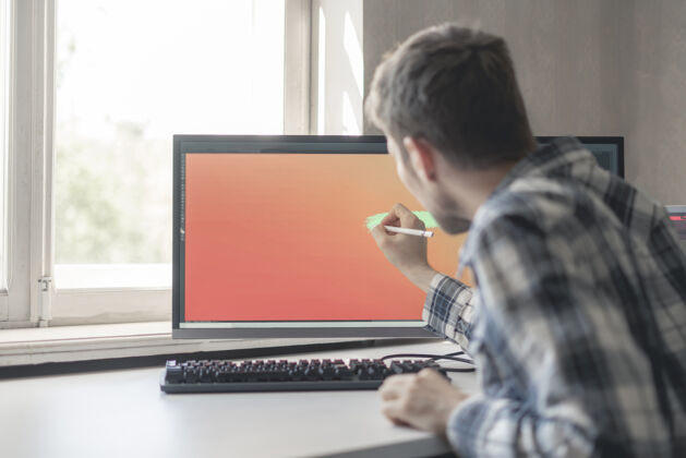 图片一位年轻的男性数码艺术家在工作室的电脑屏幕上画画手写笔绘图图形