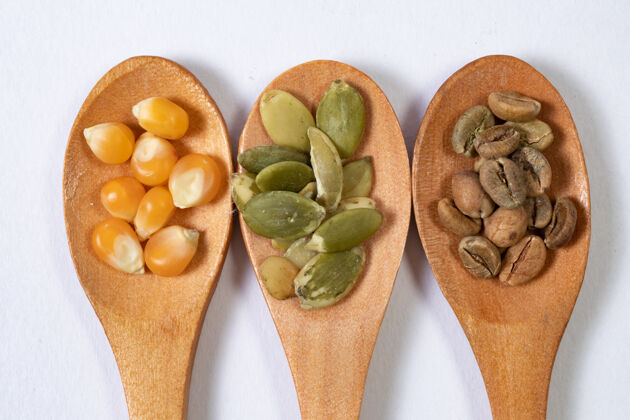 有机三种不同的种子放在白色表面的木勺里天然谷物坚果