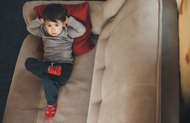 人上图：隔离检疫期间 一个白人男孩躺在沙发上 被隔离在家里小休息年轻