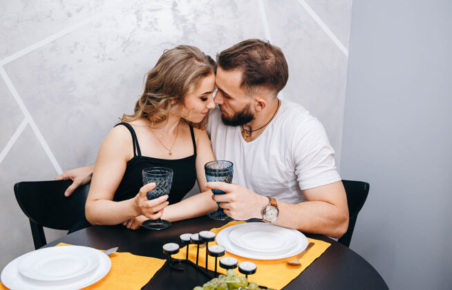 蜜月一对年轻夫妇端着酒杯在餐桌上享用浪漫的晚餐男人浪漫夜晚