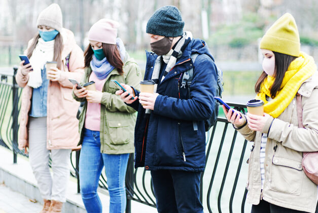 安全一群年轻人站在一个距离彼此保持距离 在冠状病毒流行帽子预防互联网