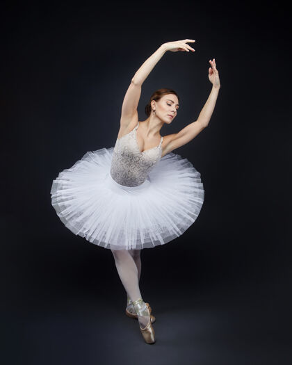 表演迷人的芭蕾舞演员在黑色背景上优雅地摆出姿势人物鞋腿
