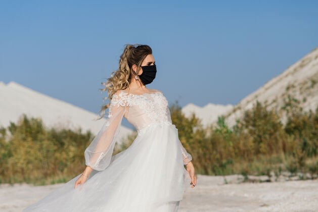 预防在冠状病毒冠状病毒-19隔离期穿着婚纱戴着医用口罩的新娘婚纱礼服订婚