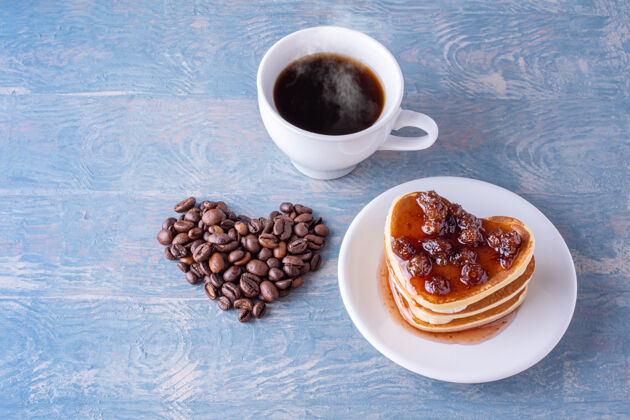 背景早餐圣瓦伦丁的白天自制的心形煎饼配浆果酱 心形内衬咖啡豆 蓝色木桌上放一杯白咖啡新鲜庆祝爱