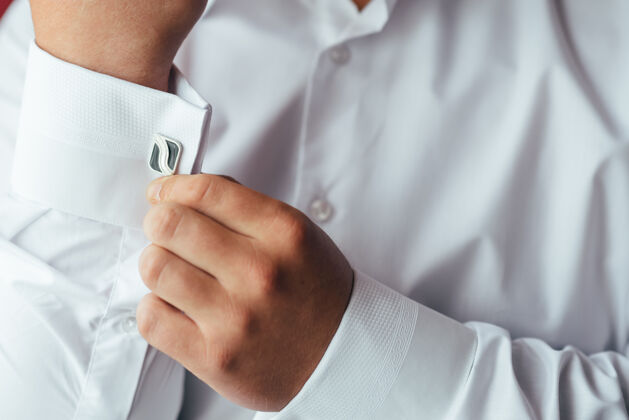 磨损男手放在一件白色衬衫的表面 袖子上有袖扣和手表 拍下了特写镜头袖口正式身体