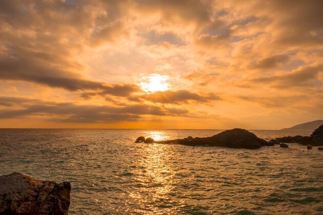 阳光岩石海岸天空中有许多金色的云和阳光风景海光线