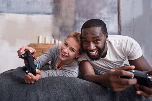 控制台我们将全神贯注年轻的国际夫妇躺在床上享受游戏机广告年轻游戏玩家