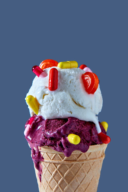 美味华夫饼蛋卷特写镜头 一团浆果和香草冰淇淋 红色和黄色胶囊 棒棒糖衬托蓝色背景夏季卡他性疾病的概念及其治疗冷冻药丸冰糕