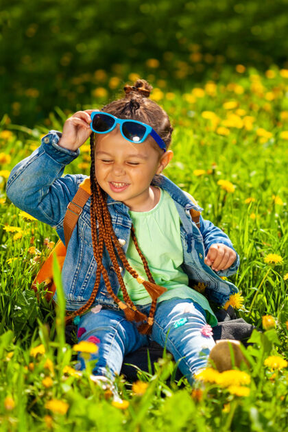 休闲时尚女婴戴着墨镜坐在草地上的大自然幼儿欢呼乐趣
