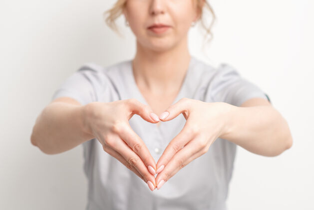 制造年轻的女美容师用手做心脏 特写女人形状形式